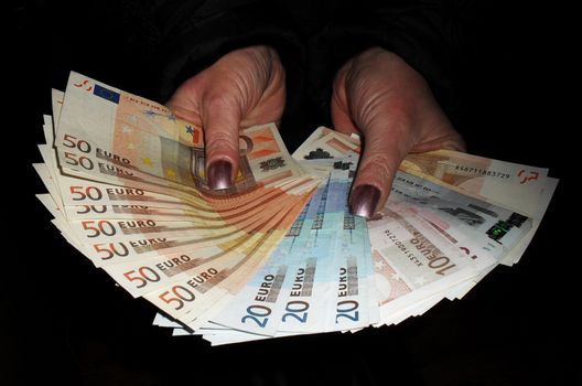 Hand full of banknotes of the European currency. Against a black background