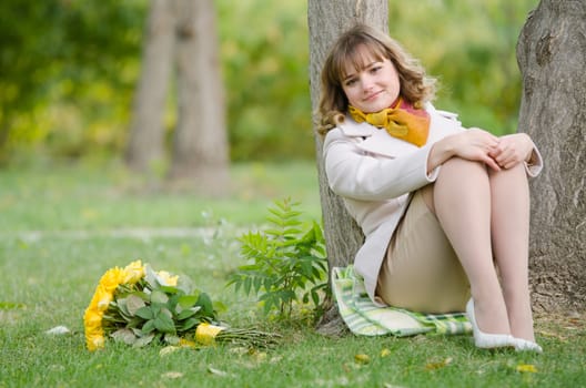 Young cute girl with a bouquet of yellow roses in autumn cool weather