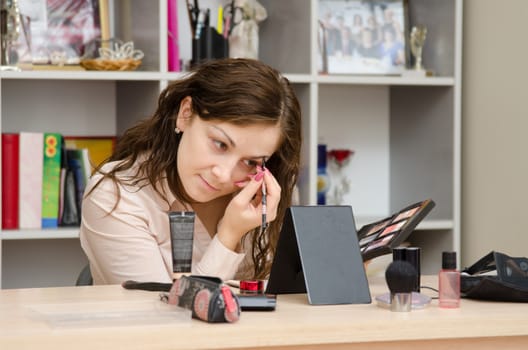 Young girl puts makeup in the office workplace