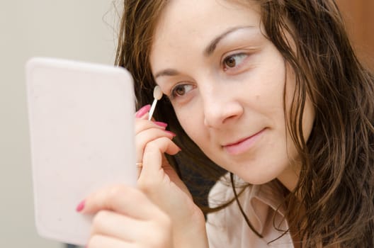 Young girl puts makeup in the office workplace