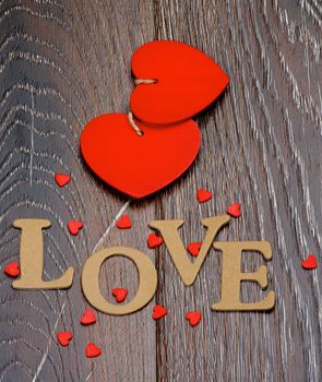 Two Red Hearts and Cardboard Word Love closeup on Dark Wooden background