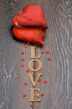 Two Wooden Red Hearts and Cardboard Word Love isolated on Dark Hardwood background