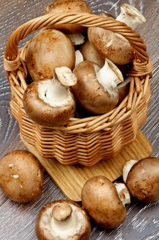 Delicious Raw Portabello Mushrooms in Wicker Basket closeup on Hardwood background