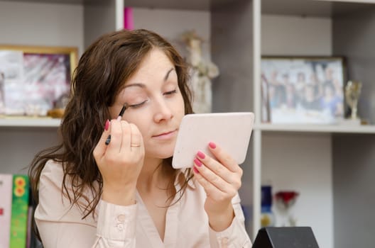 A young girl puts makeup in the office workplace
