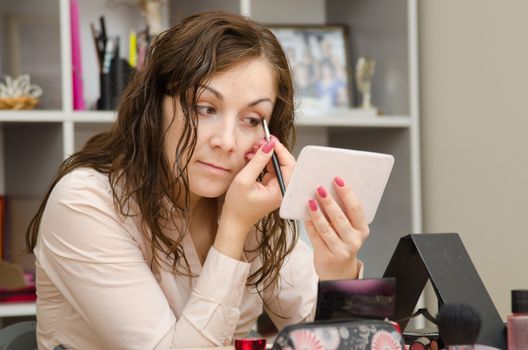 A young girl puts makeup in the office workplace