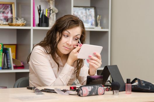 A young girl puts makeup in the office workplace