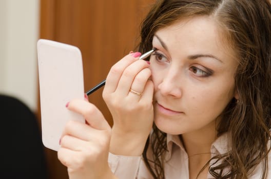 A young girl puts makeup in the office workplace