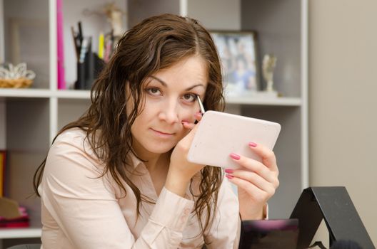 A young girl puts makeup in the office workplace