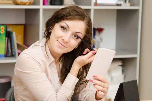 A young girl puts makeup in the office workplace