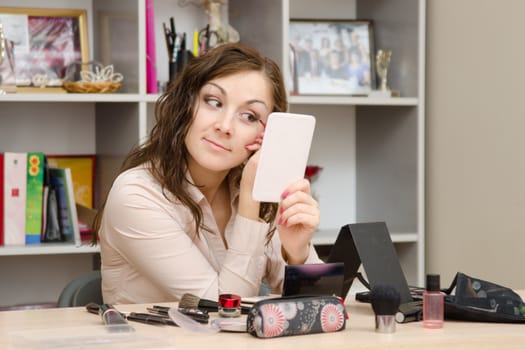 A young girl puts makeup in the office workplace
