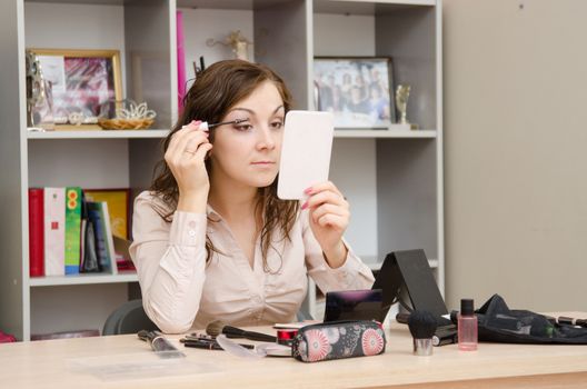 A young girl puts makeup in the office workplace