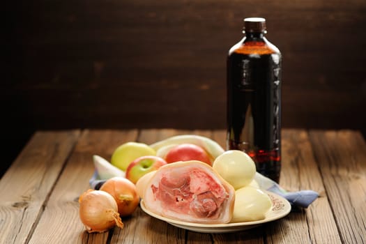 Ingredients for eisbein: pork, onion, apples and beer on wooden background