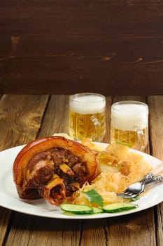 Eisbein with light beer  with sauerkraut on wooden background vertical