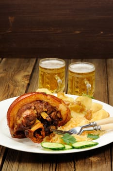 Eisbein with light beer  with sauerkraut on wooden background vertical