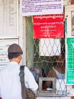 Yangon, Myanmar - November 13, 2014: Man buying a ticket at Pan Hlaing Railway Station in Yangon, Myanmar. Myanmar has a large railway network, but stations as well as trains are old and worn down.