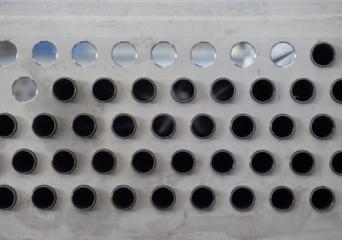 Metal plate with holes and pipes, part of an industrial air-cooled condenser under production.