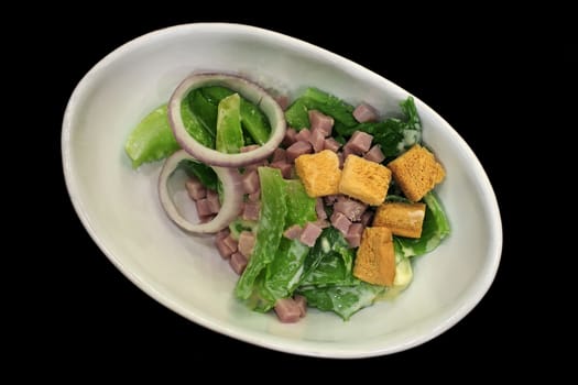 delicious caesar salad with ham on black background       