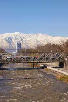 Snow covered mountains surrounding the city of Santiago, capital of Chile. View from a bridge across the Mapocho River in central Santiago.