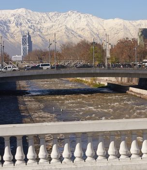 Snow covered mountains surrounding the city of Santiago, capital of Chile. View from a bridge across the Mapocho River in central Santiago.