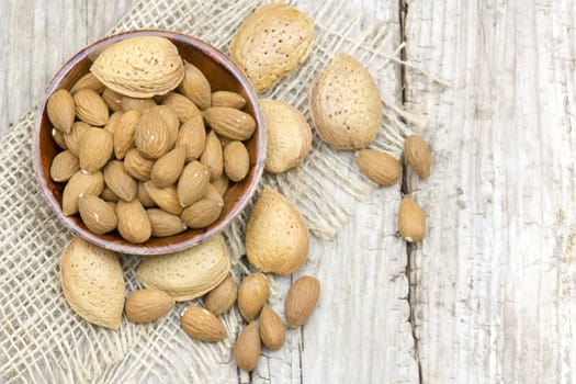 almonds in a bowl on old wooden background