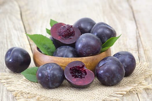 fresh plums in a bowl on old wooden background