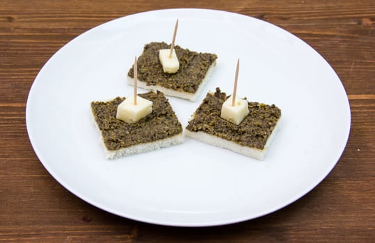 Canapes with olive paste on wooden table