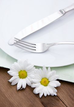 Cutlery on plate with flowers on wooden table