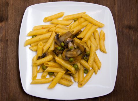 Pasta with mushrooms and peas on wooden table top view