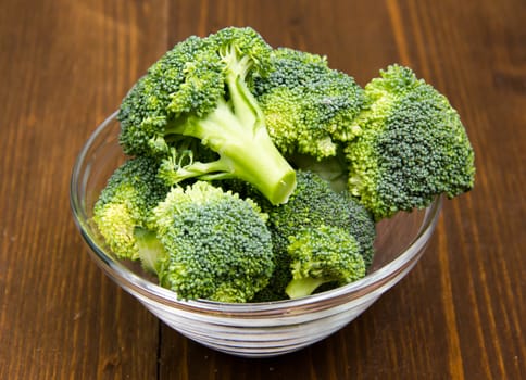 Broccoli in glass bowl on wooden table