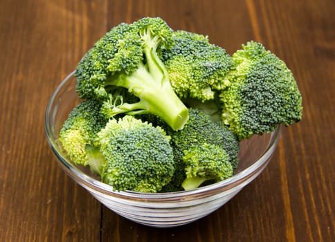 Broccoli in glass bowl on wooden table