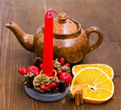 Christmas candle with orange and cinnamon on wooden table