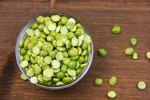 Dried peas in bowl on wooden table seen from above