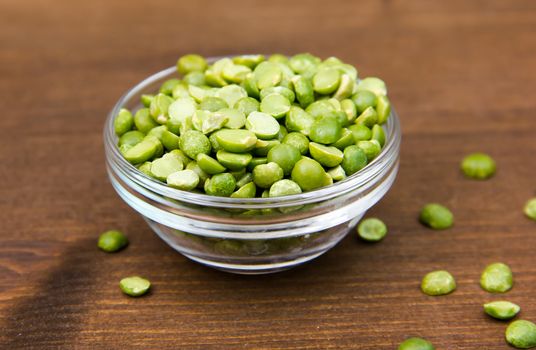 Dried peas in bowl on wooden table