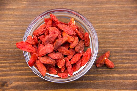 Goji berries in bowl on wooden table top views