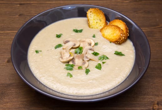 Cream of mushrooms on plate on wooden table