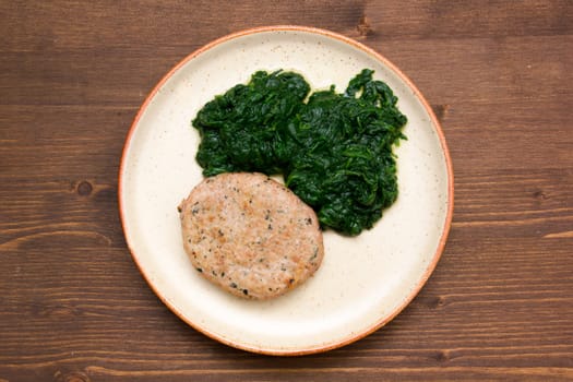 Hamburger meat with spinach on wooden table seen from above