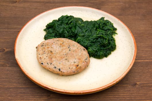Hamburger meat with spinach on wooden table