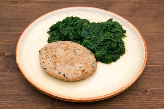 Hamburger meat with spinach on wooden table