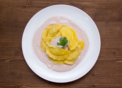 Ravioli with radicchio sauce on wooden table seen from above