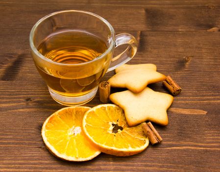 Tea and biscuits with orange and cinnamon on wooden table