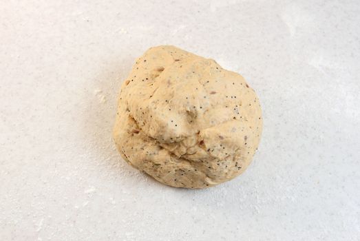 Smooth ball of freshly-kneaded multi seed bread dough on a floured worktop 
