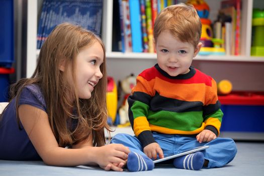 Girl with her little brother fun using a digital tablet computer