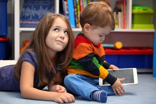 Disappointing girl with her little brother using a digital tablet computer