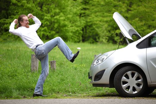 Driver furious a broken car by the road  