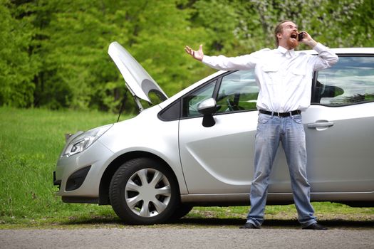 Driver furious with mobile phone a broken car by the road