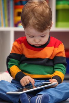 Happy 2 years old boy using a digital tablet computer