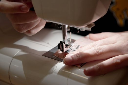 Detail of hands working on piece of fabric on automatic sewing machine