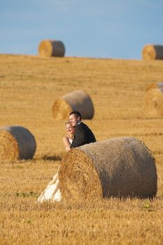 newly-wed couple in their wedding clothes in field of hay