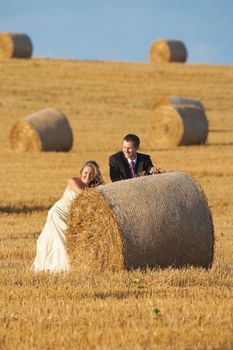 newly-wed couple in their wedding clothes in field of hay