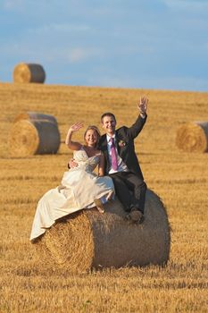 newly-wed couple in their wedding clothes in field of hay